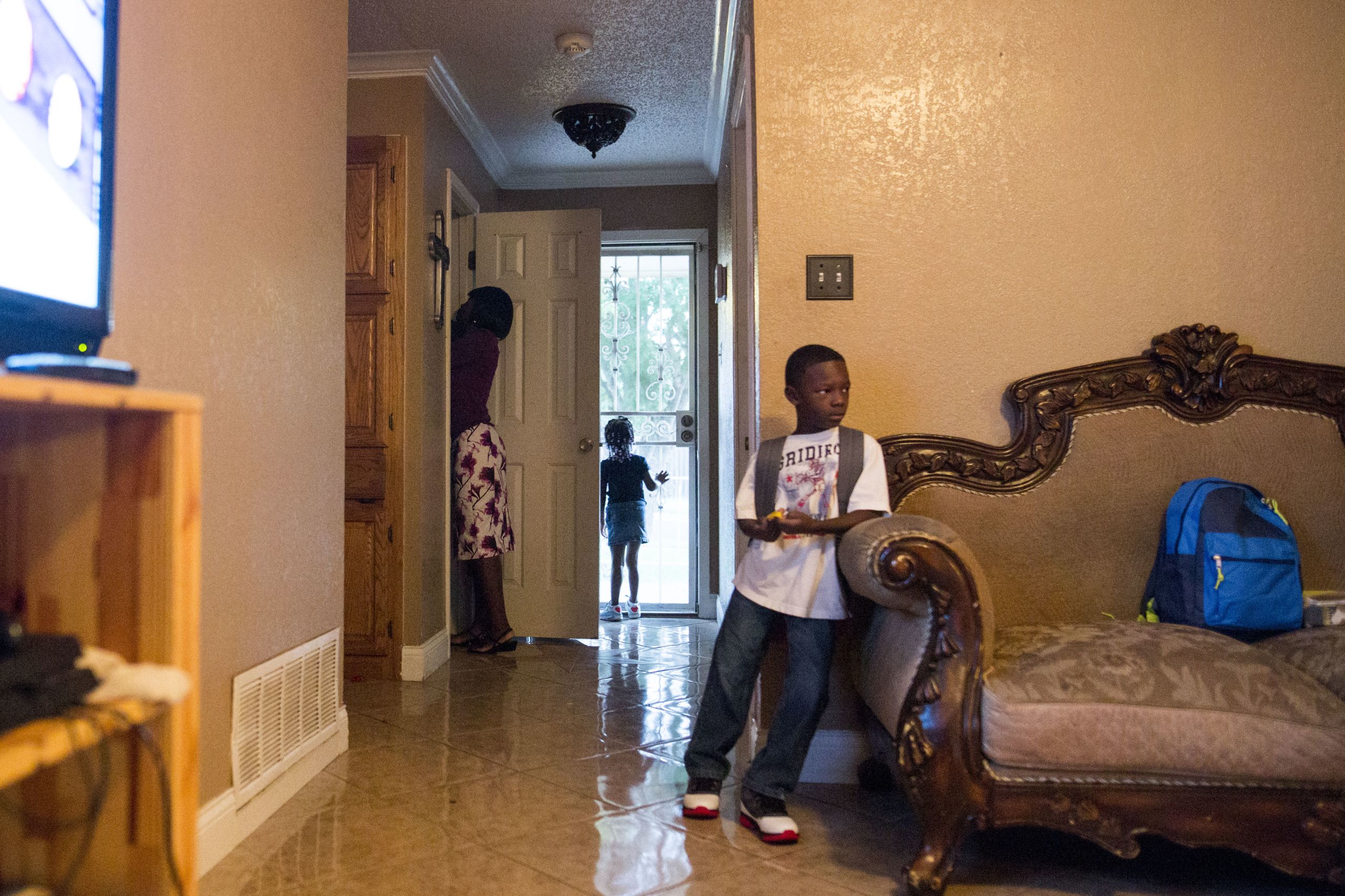 Phillips gets a car seat out of a closet before driving her children, Leah and Chris, to their first day of school.